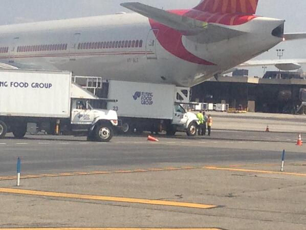 Catering vehicle stuck under plane